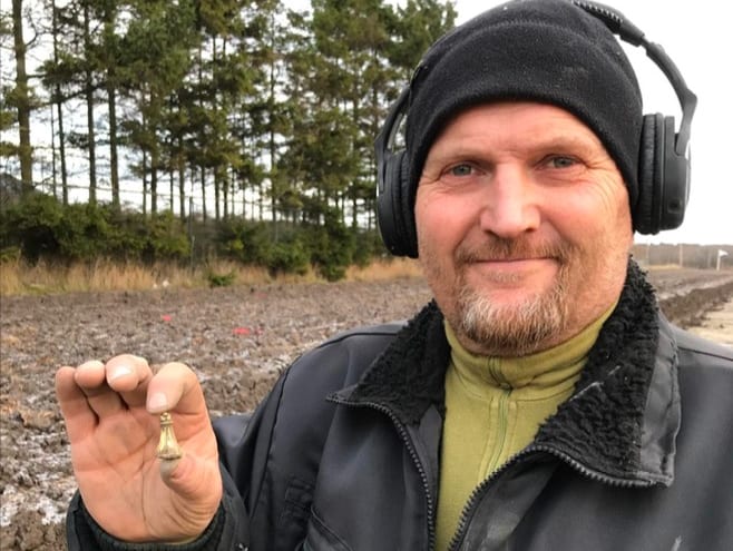 Tom Knigge holder gullberlokken som han fant på Rolvsøy. Foto: Østfold Fylkeskommune