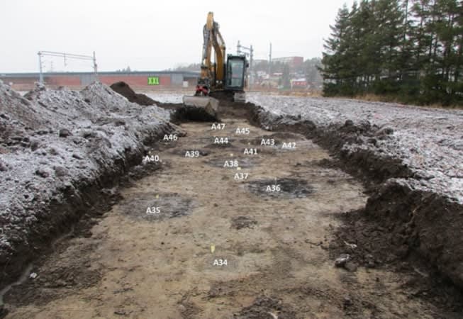 Bildet viser hvordan funnene kommer til syne når gravemaskinen jobber seg skånsomt bortover jordet. Foto: Østfold Fylkeskommune